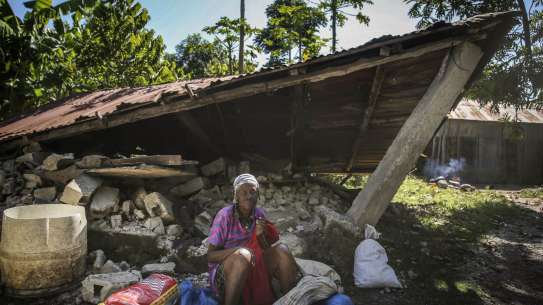 Woman sits in front of a destroyed house after the earthquake in Camp-Perrin, Les Cayes, Haiti