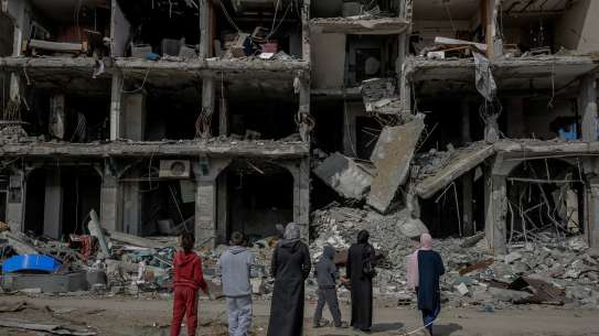 A family looks at an apartment block destroyed by a missile strike. 