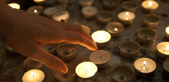 Hand reaching towards reflective candles
