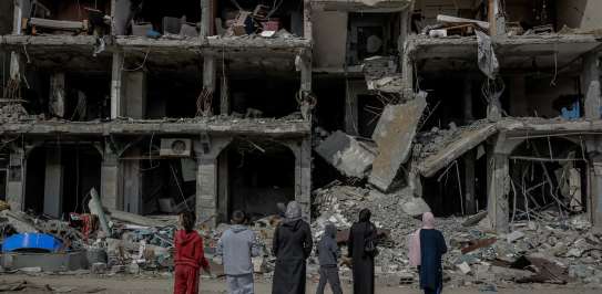 A family looks at an apartment block destroyed by a missile strike. 