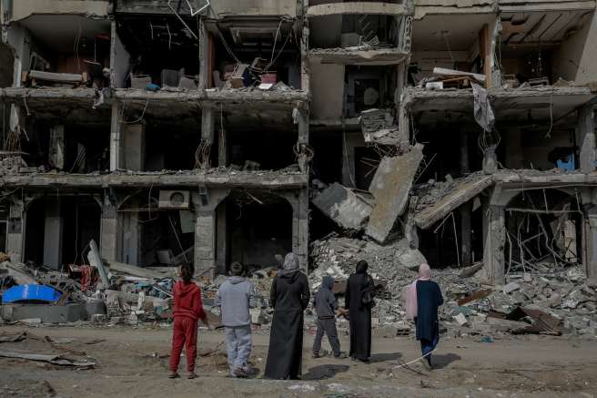 A family looks at an apartment block destroyed