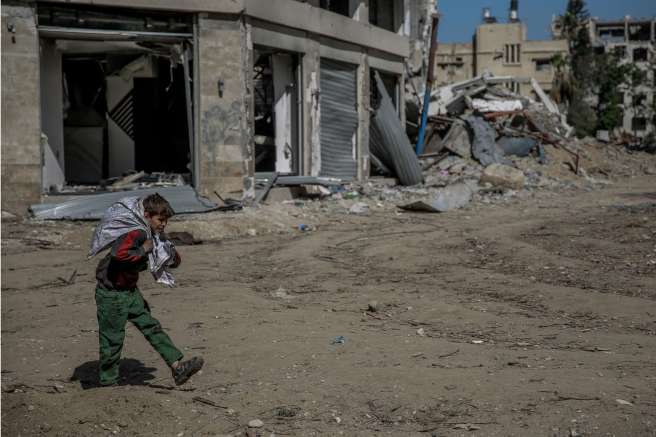 Boy carries bag through rubble