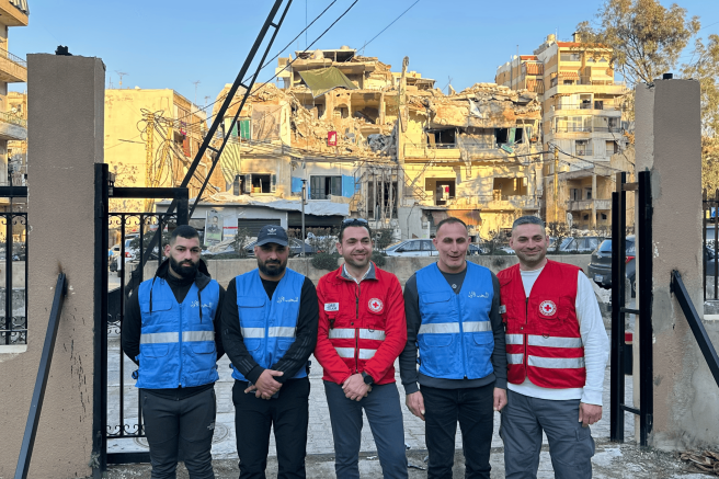 Aid workers stand in front of buildings destroyed by airstrikes 