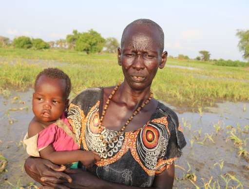 Asunta stands in her flooded farm in South Sudan
