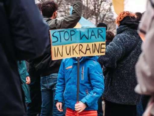 Small child holds placard calling for the war in Ukraine to be stopped.