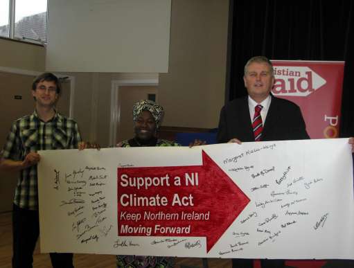 Jim Wells is presented with a banner by Christian Aid supporters at a Bearing Witness event in Comber