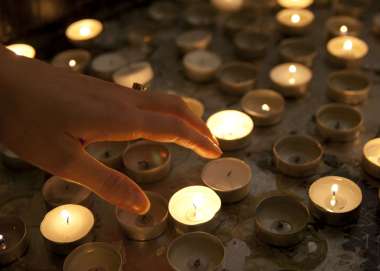Hand reaching towards reflective candles