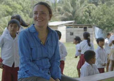 Eleri Davies is sitting with children at a school in Bolivia