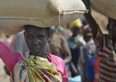 A displaced woman carries a bag of grain in South Sudan