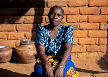 Woman sits beside house in Malawi