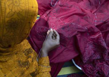A young Bangladeshi woman sewing a star