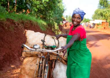 Woman with loaded bicycle in Burundi smiles