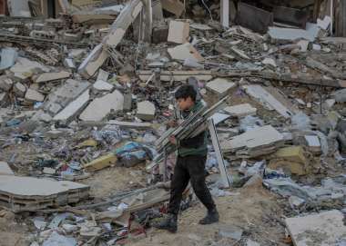 Boy carrying wood through rubble